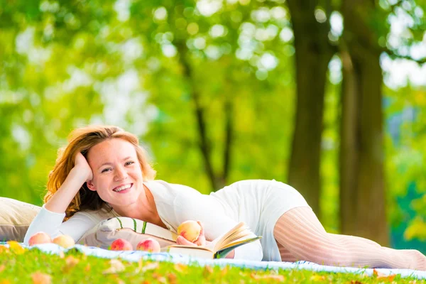 Braunäugiges Mädchen mit Äpfeln und einem Buch im Park — Stockfoto