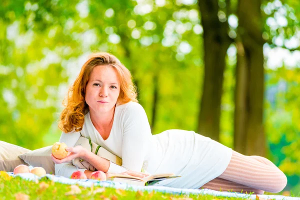 Woman with an apple resting on the weekend in the park — Stock Photo, Image