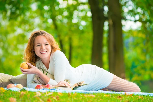Glad tjej med ett vackert leende ensam i parken med en pic — Stockfoto