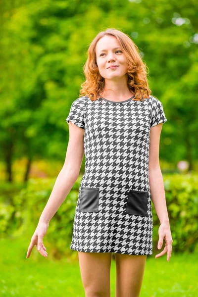 Fille heureuse dans une robe sur un fond de parc vert — Photo