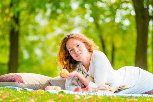 Portrait of young girl with books and apple on the plaid in the Stock Image