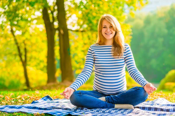 Glad gravid kvinna avkopplande på gräsmattan i parken — Stockfoto