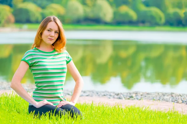 Çim ve güzel gülümsüyor üzerinde oturan genç kız — Stok fotoğraf
