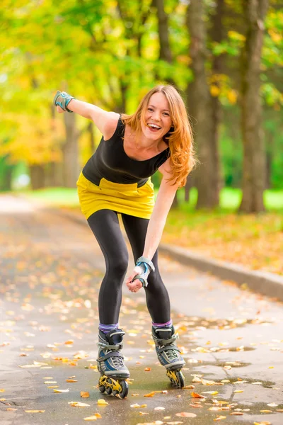 秋の公園でアクティブな陽気な美少女のローラー スケート — ストック写真