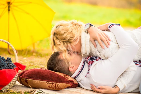 Kissing couple on the plaid in autumn park — Stock Photo, Image