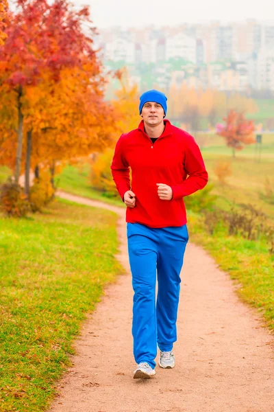 Manliga friidrottare jogga på morgonen i parken — Stockfoto