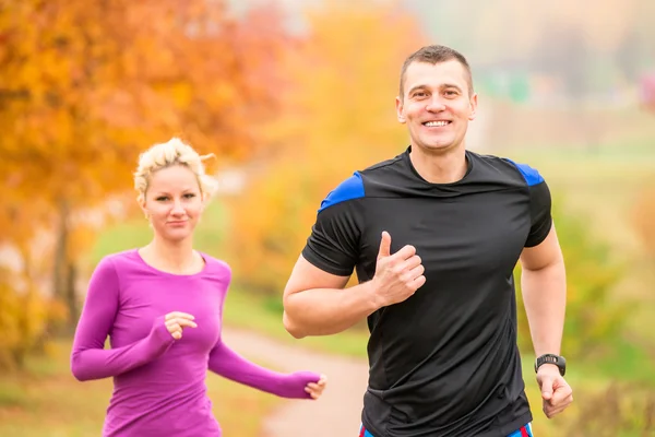 Cheerful young athletes jogging autumn morning — Stock Photo, Image