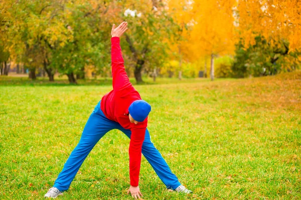 Утром разминка молодого спортсмена на поляне в парке осенью — стоковое фото
