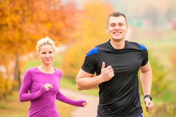Cheerful young athletes jogging autumn morning Royalty Free Stock Images