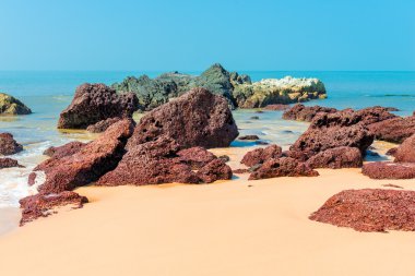 güzel kahverengi taş, sarı kum ve mavi deniz