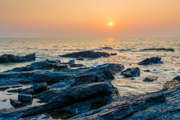 海と岩の多い海岸の上の明るいオレンジ色の太陽 — ストック写真