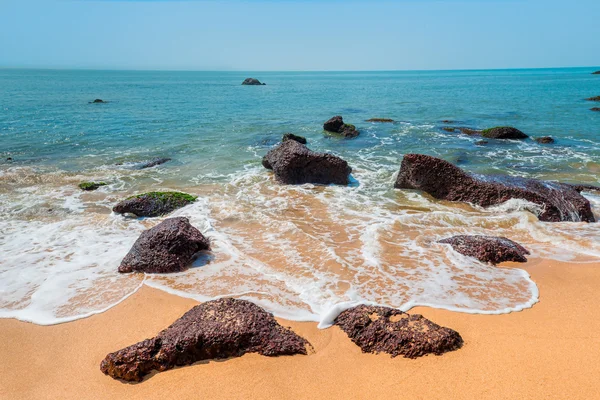 Rocas grandes en la arena y oleaje espumoso — Foto de Stock