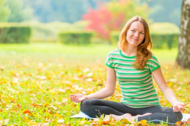 gülümseyen kız sonbahar parkta yoga yaparken