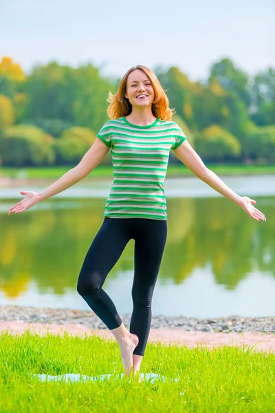 Belle fille aux cheveux roux rit et effectue des exercices — Photo