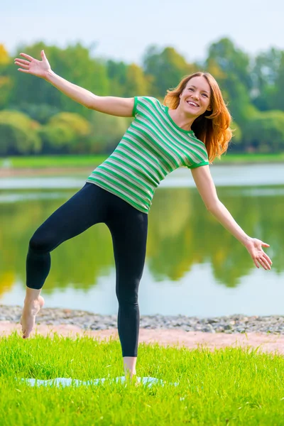 Glad flicka försöker hålla balansen på ett ben — Stockfoto