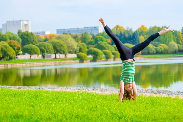 Barfota flicka står på händer på gräsmattan — Stockfoto