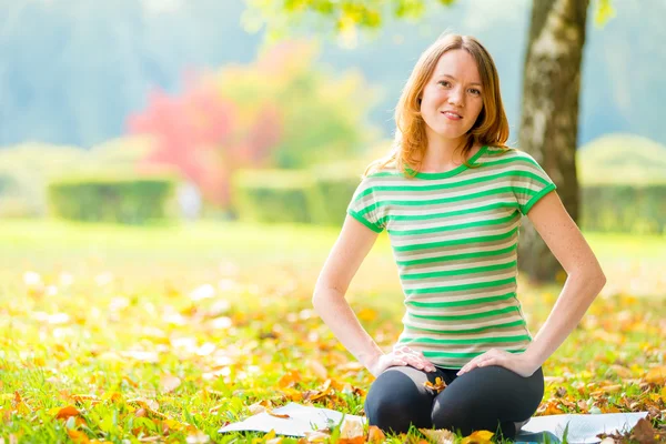 Niña en el parque de otoño por la mañana practicando yoga —  Fotos de Stock