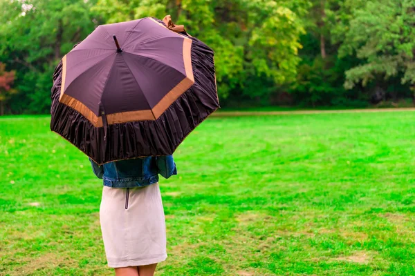 Mujer de pie en el prado bajo el paraguas abierto — Foto de Stock