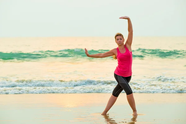 Active young woman doing exercises on a background of the sea — Stock Photo, Image