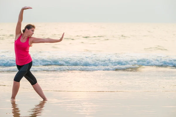 Donna concentrata che fa yoga sulla spiaggia — Foto Stock