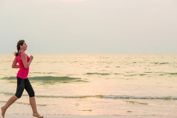 ผู้หญิงวิ่งเท้าเปล่าบนชายหาดทราย — ภาพถ่ายสต็อก