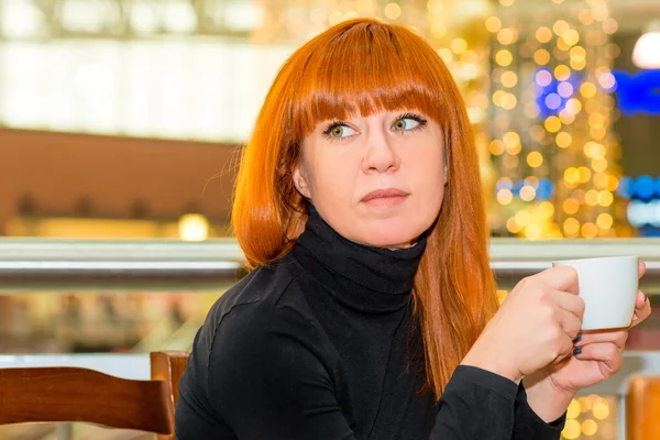 Vrouw met een kop in een café — Stockfoto