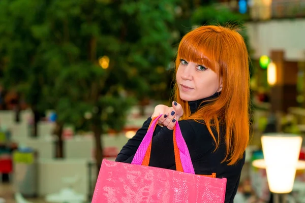 Roodharige meisje met shopping tassen in het winkelcentrum — Stockfoto