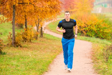 athletic man running in the park on a footpath