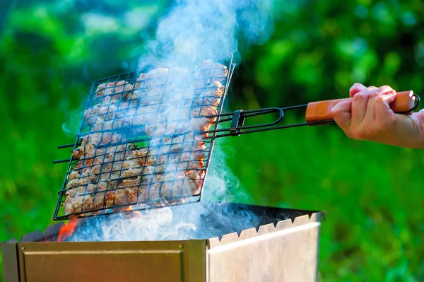 Woman's hand turning meat on the grill — Zdjęcie stockowe