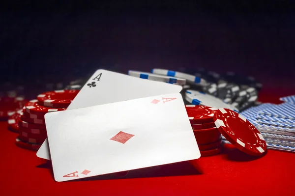 Due assi e un mucchio di fiches da poker su un tavolo rosso — Foto Stock