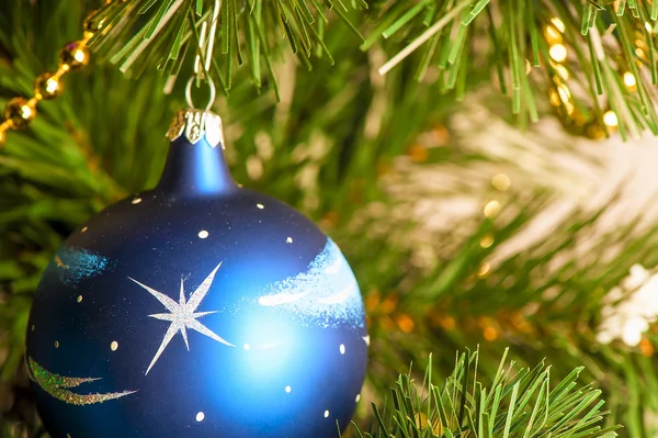 Blue Christmas ball on a branch of artificial fir — Stock Photo, Image