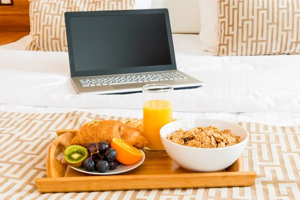 Breakfast in bed and a laptop in the room — Stock Photo, Image