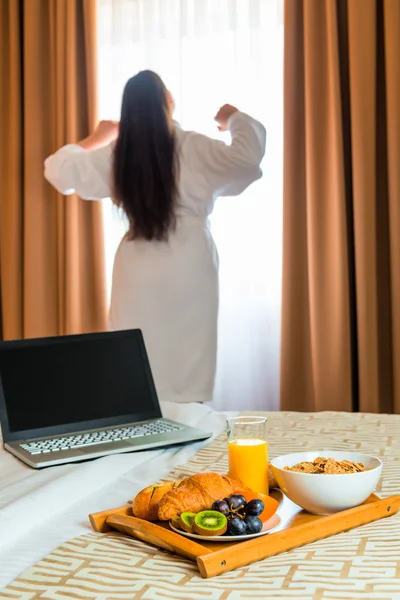 Woman in a bathrobe stretches in the morning near the window — Stock Photo, Image