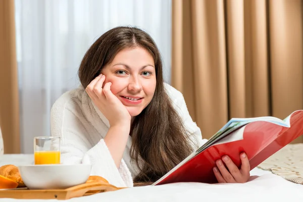 Portrait of a beautiful woman with a magazine in the room — Stockfoto