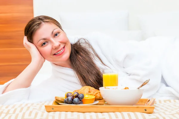 Happy beautiful girl on the bed with a tray of food — Stockfoto