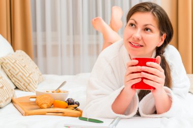 thoughtful girl with notepad and breakfast in bed