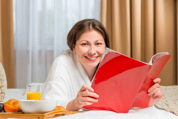 Reading a magazine on the bed in the morning — Stock Photo, Image