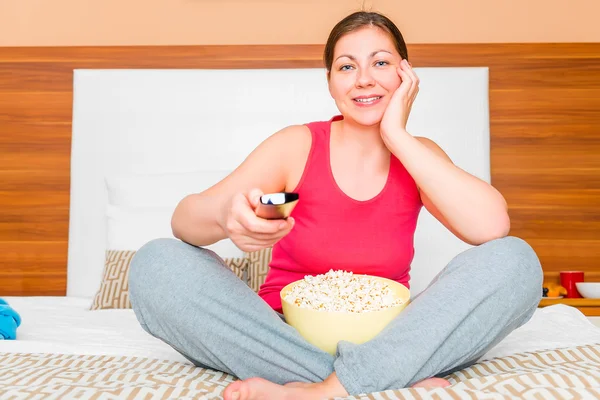 Chica con un tazón de palomitas de maíz viendo un divertido programa en la televisión —  Fotos de Stock