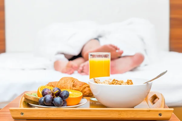 Couples feet luxuriate in bed and a tray of food — Stock Photo, Image