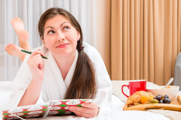 Mujer joven con un cuaderno y desayuno en la cama — Foto de Stock