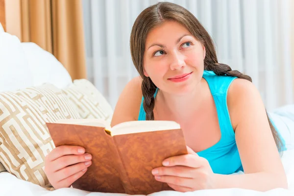 Attraktives junges Mädchen mit interessantem Roman im Bett — Stockfoto