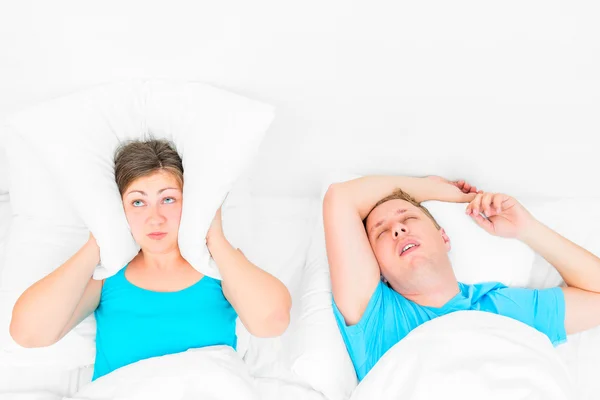 从丈夫打鼾，覆盖他的枕头睡不着的女人 — 图库照片