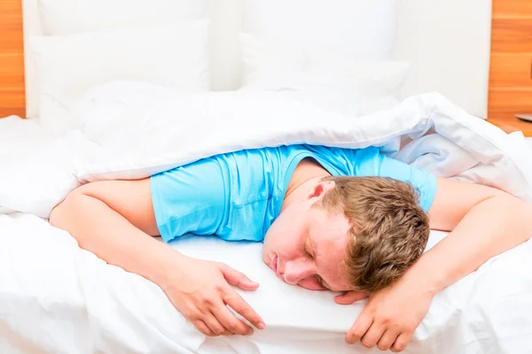 Homem dormindo em uma cama branca lençóis — Fotografia de Stock