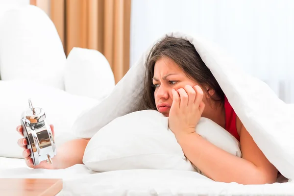 Beautiful girl with an alarm clock in the hands slept on the job — Stock Photo, Image