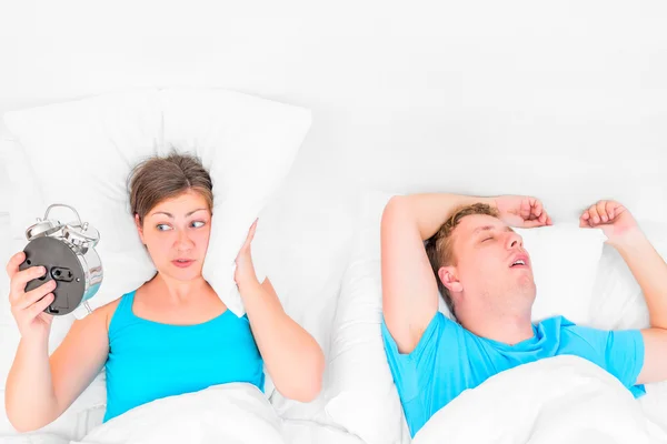 Woman with an alarm clock listening to the snoring husband — Stock Photo, Image