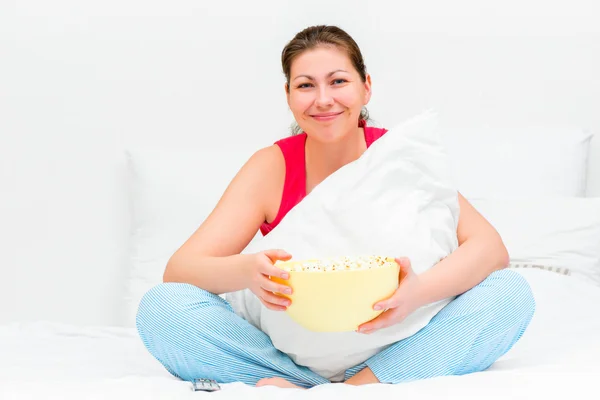 Morena sonriente con un tazón de palomitas de maíz viendo la televisión — Foto de Stock