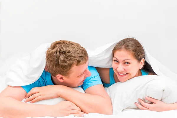 Young beautiful couple in bed under a blanket — Stock Photo, Image