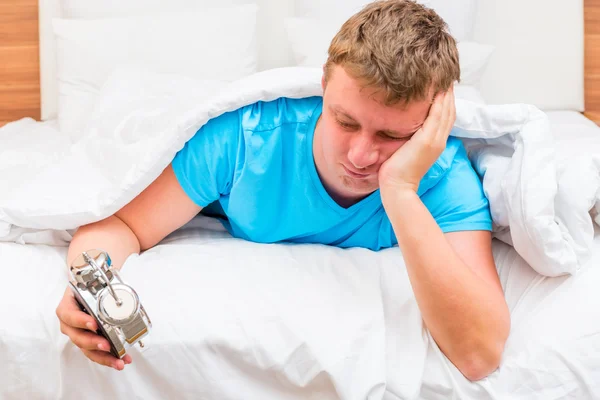 Annoyed man with an alarm clock in the hands of suffering from i — Stock Photo, Image