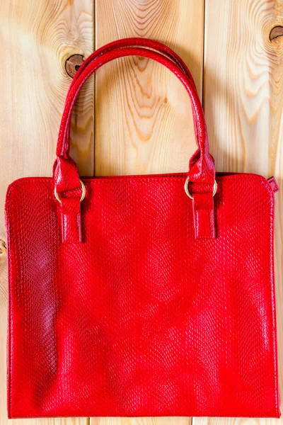 Saco vermelho feminino de um couro genuíno em um fundo de madeira — Fotografia de Stock