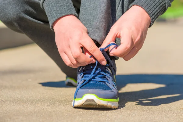 Mani di uomo close-up legato lacci di scarpe sull'asfalto — Foto Stock